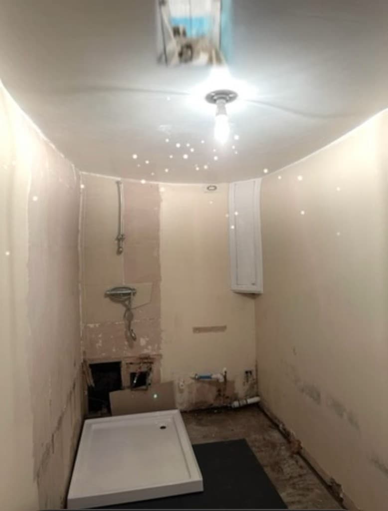 Bathroom before tiling, with stripped walls, a shower tray and unfinished surfaces