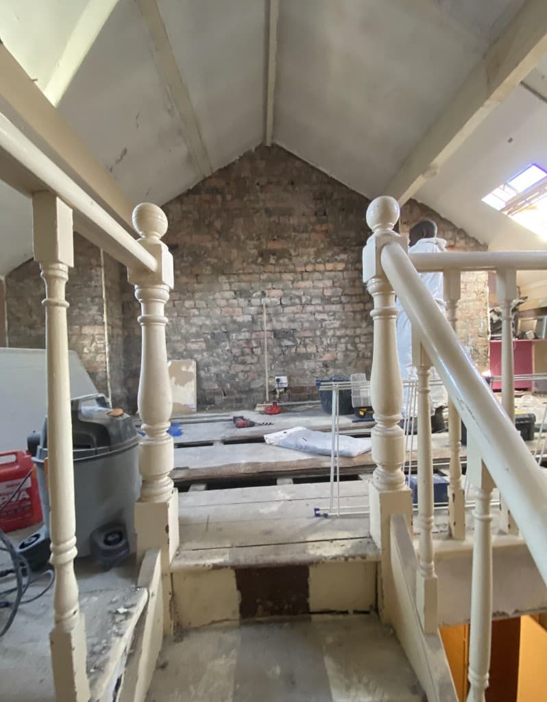 Loft space during renovation, with exposed brick and floor structure open