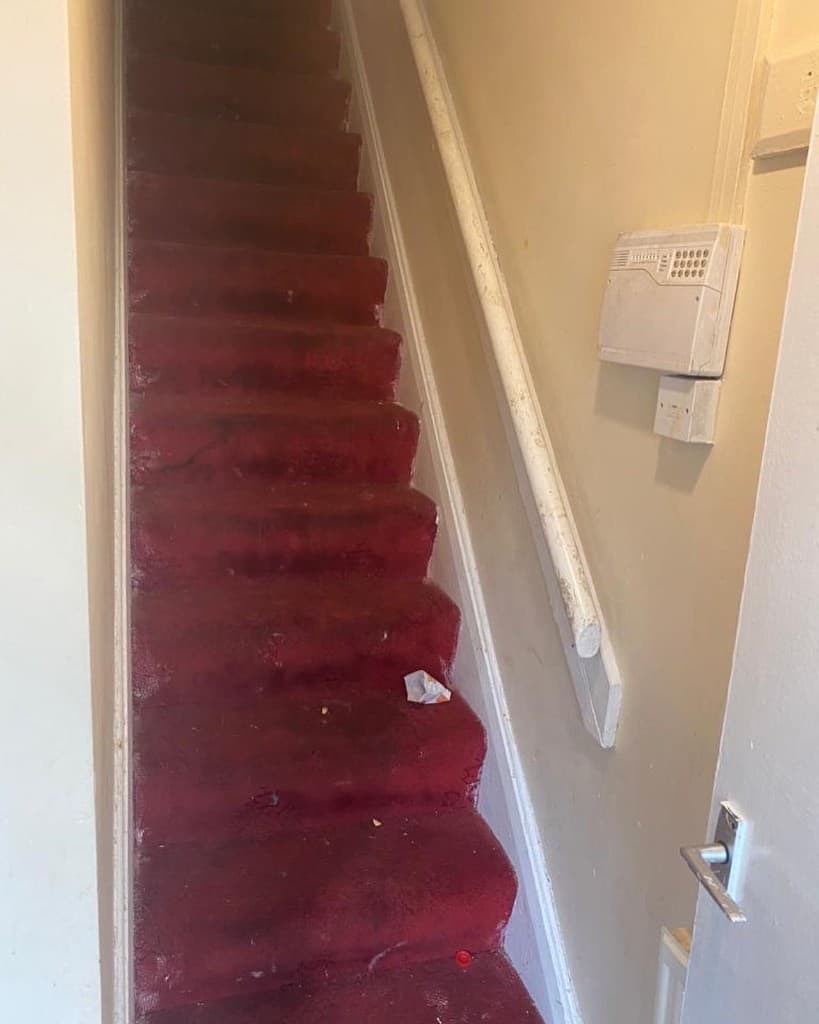 Staircase before refurbishment, still covered in red carpet
