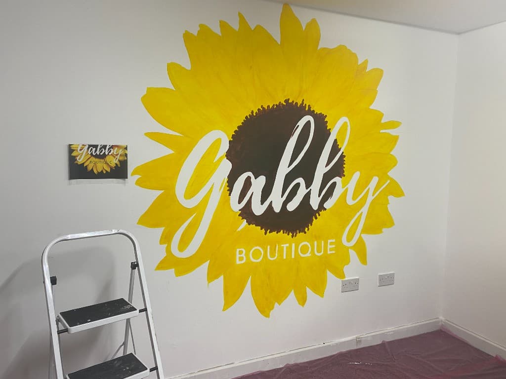 Finished hand-painted sunflower mural reading Gabby Boutique