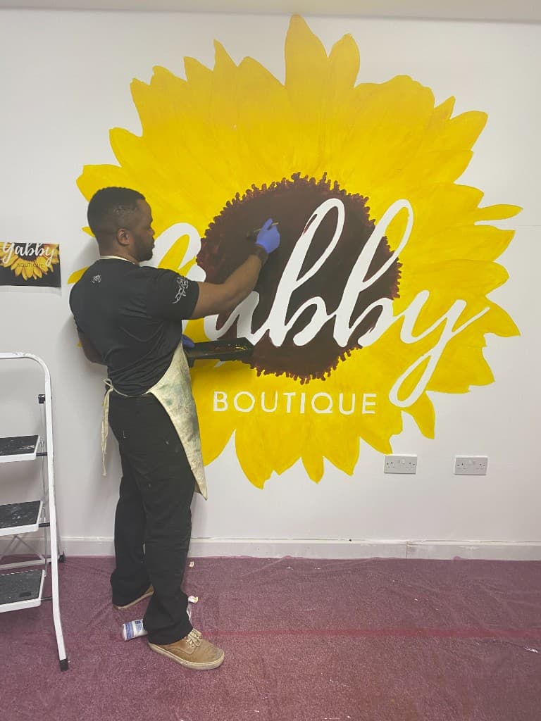 Hand-painted sunflower mural being completed on a feature wall